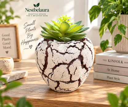 A Nestbelaura faux succulent plant in a textured, round ceramic pot with a crackled beige and brown finish, styled on a wooden table with books and other plants.