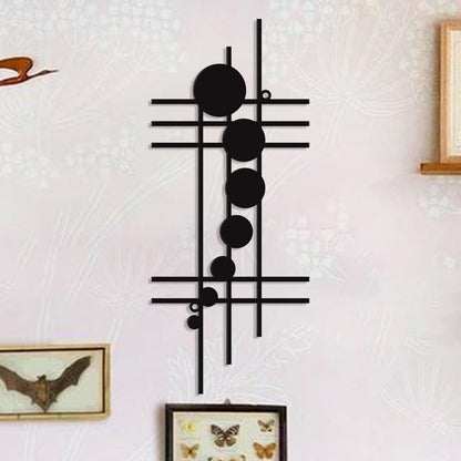 Decorative wall art with black geometric design on a textured white wall.